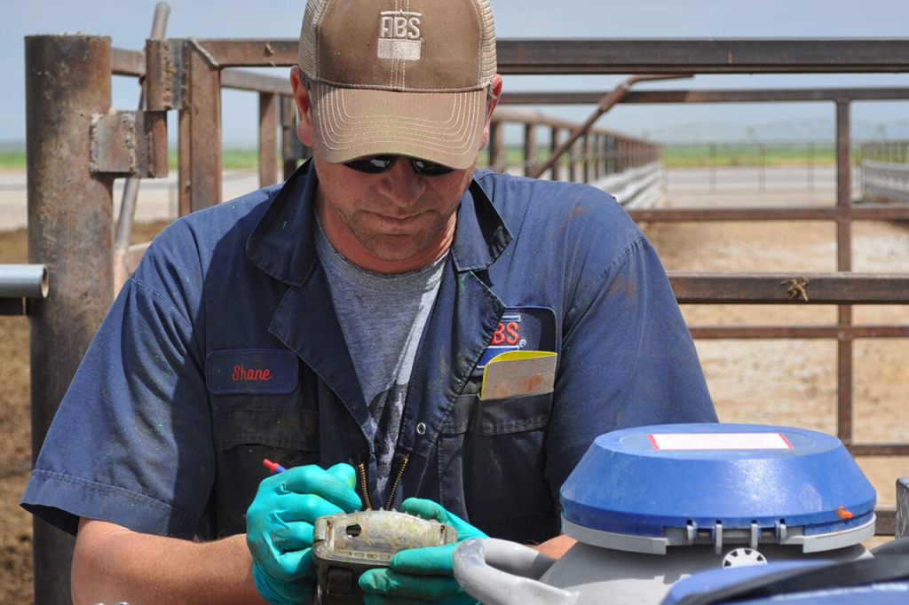 ABS breeder looking at handheld by a semen tank